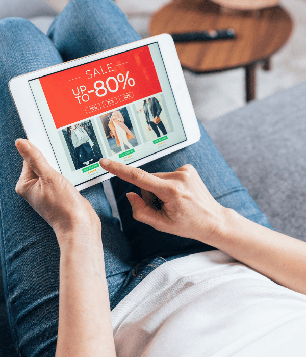 persona vestida con jeans sostiene una tablet en la cual revisa ofertas